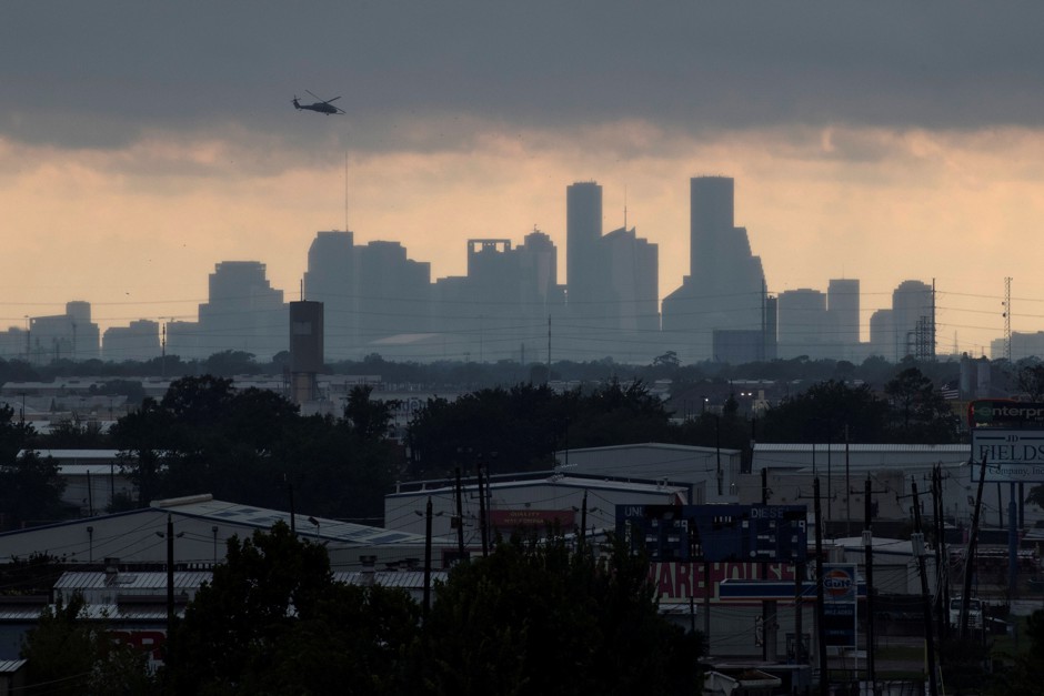 A helicopter hovers above the Houston skyline as sunlight breaks through storm clouds from Tropical Storm Harvey.