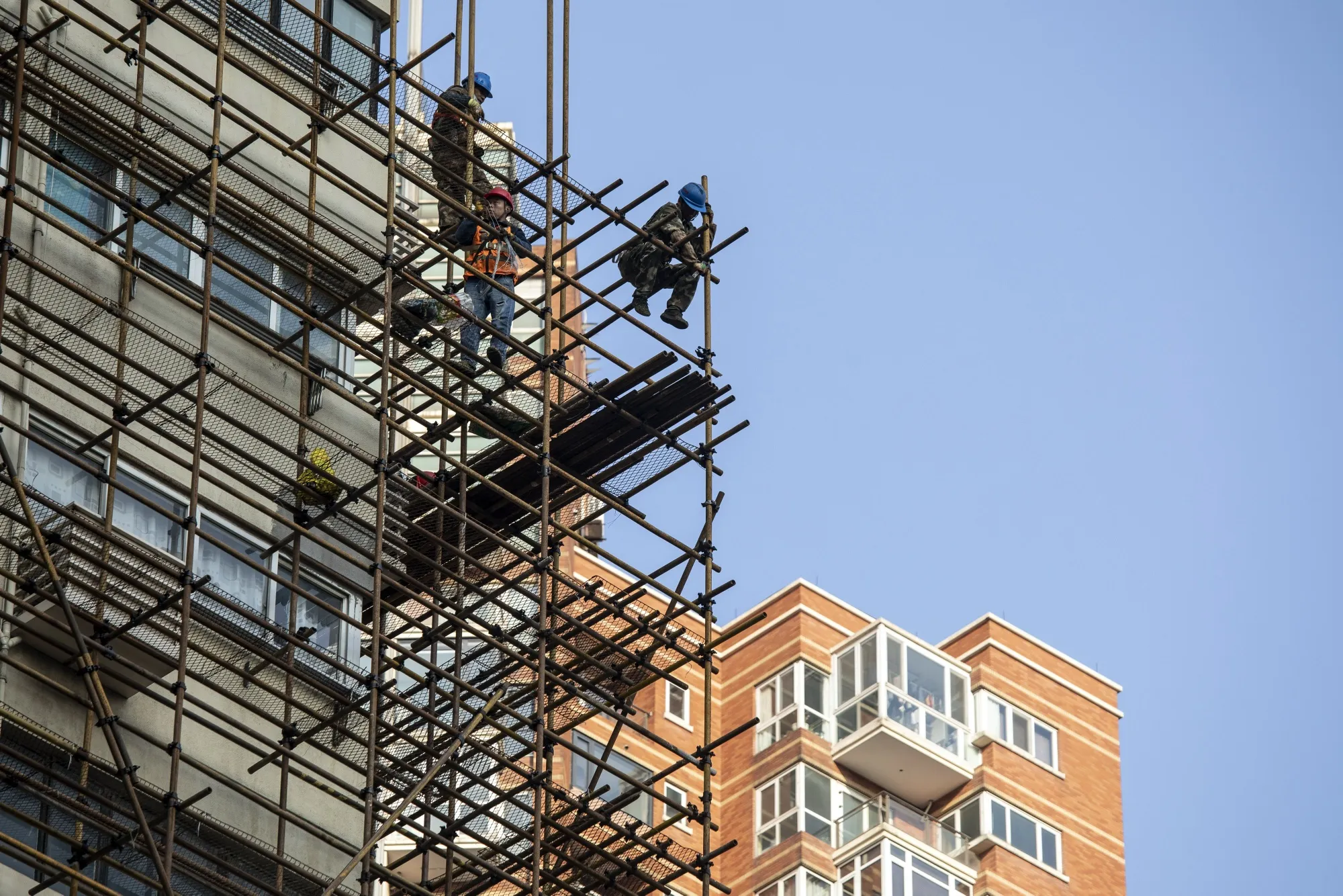 Workers stand on a scaffolding in Shanghai on Feb. 27. China’s Politburo vowed to strengthen macroeconomic policies to stabilize the economy this year, suggesting more support could be coming to boost growth ahead of a key leadership meeting later this year.