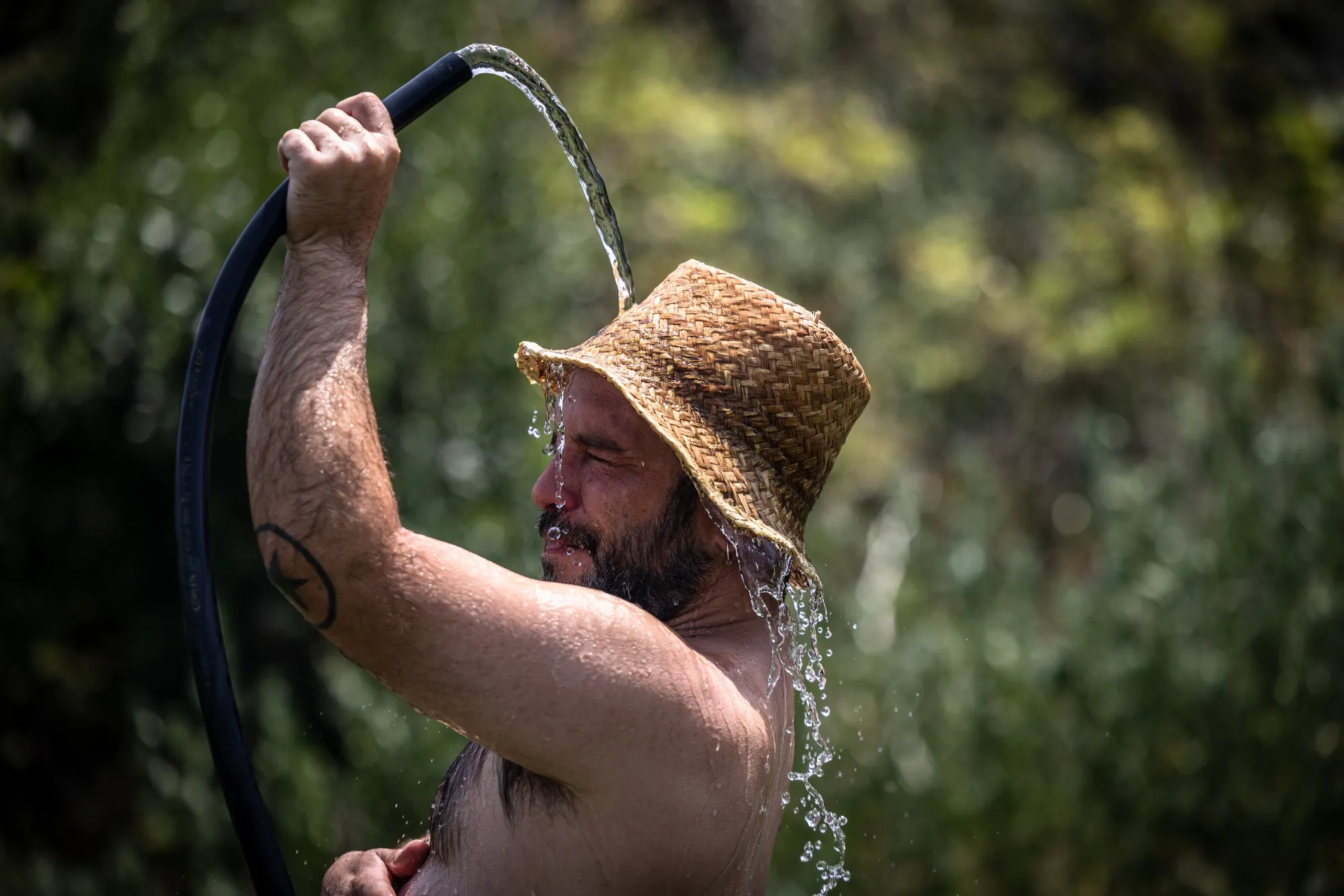 A farmer hoses himself with water to keep cool during high temperatures in Llad, Spain.