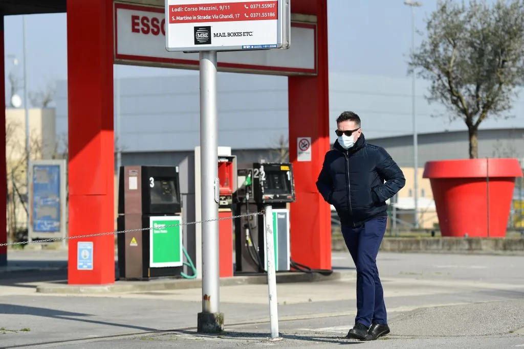 A man wearing a surgical mask walks past a gas station in Codogno, southeast of Milan.