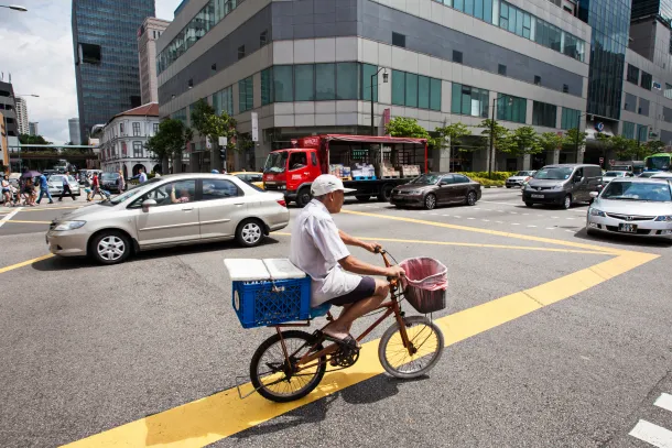 A man cycles past traffic at a junction on South Bridge Road in the Chinatown area of Singapore.