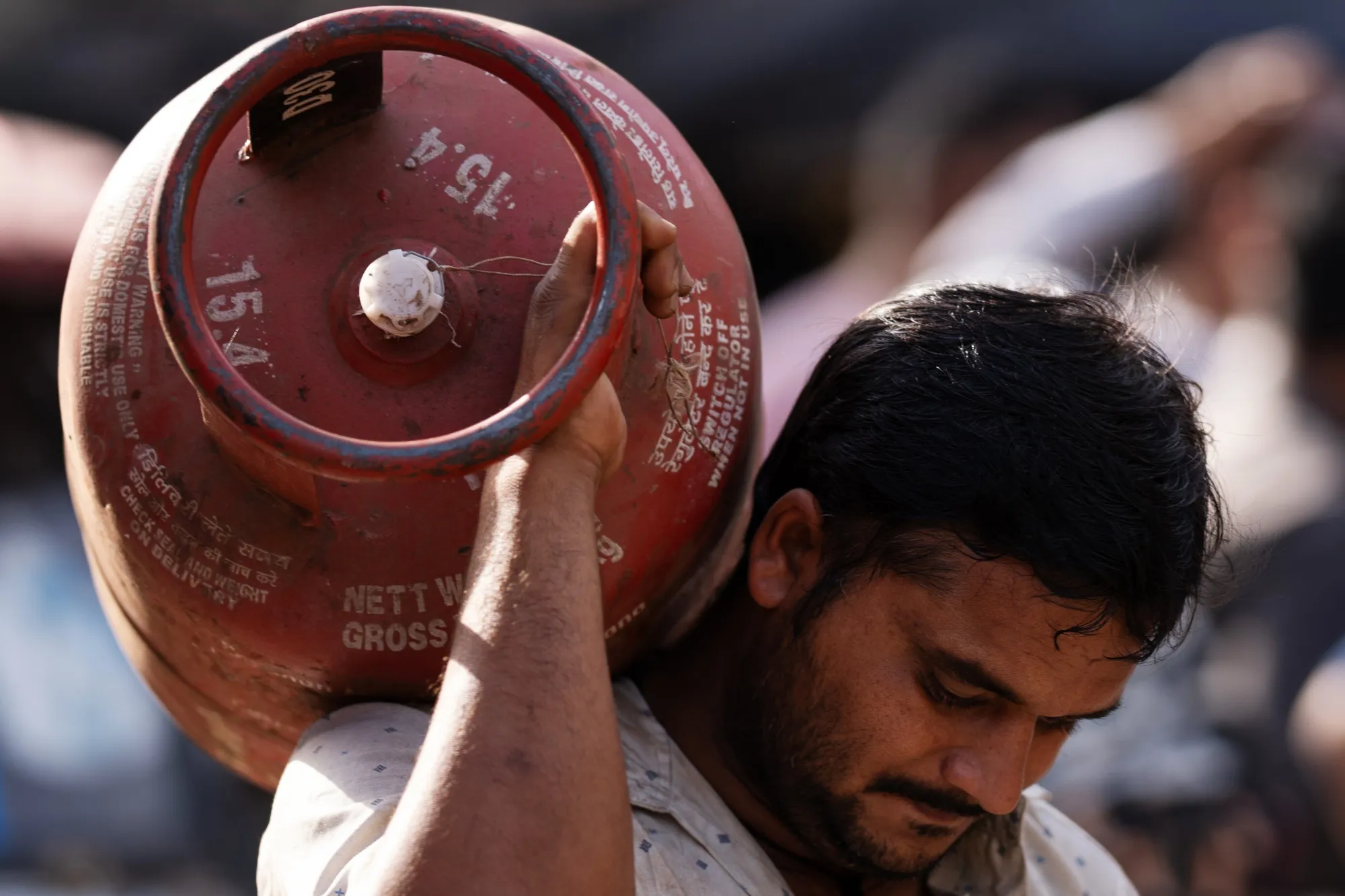 A man brings a depleted liquefied petroleum gas canister to a depot in New Delhi, India.