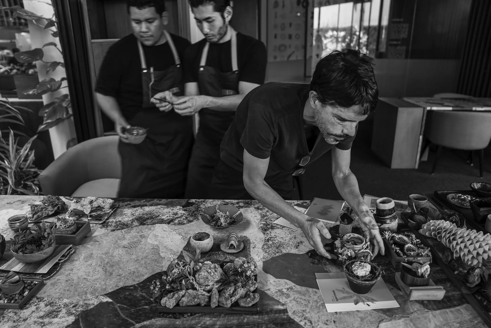 Black and white image of three men assembling small dishes. 