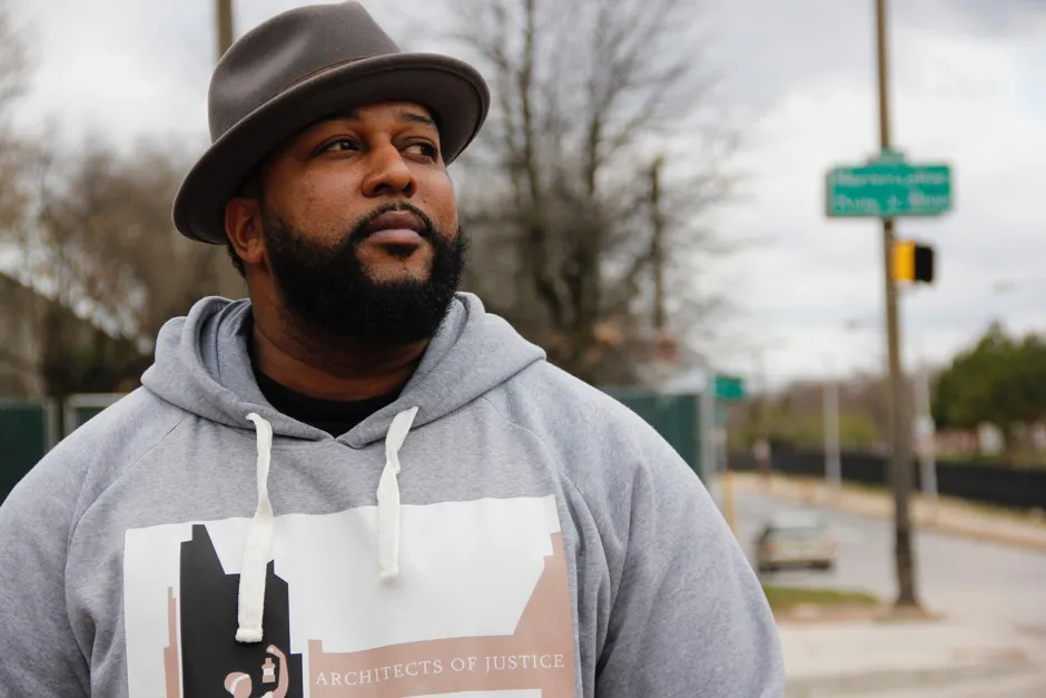 Community organizer John Comer reflects on the problems faced by the black communities in West Baltimore in front of Martin Luther King Jr. Boulevard.