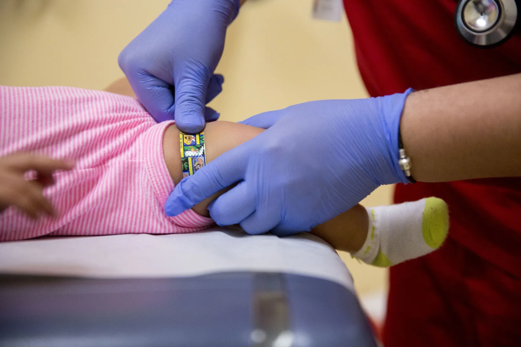 A medical assistant applies a bandage to an infant's leg after administrating a vaccine in Silver Spring, Maryland.
