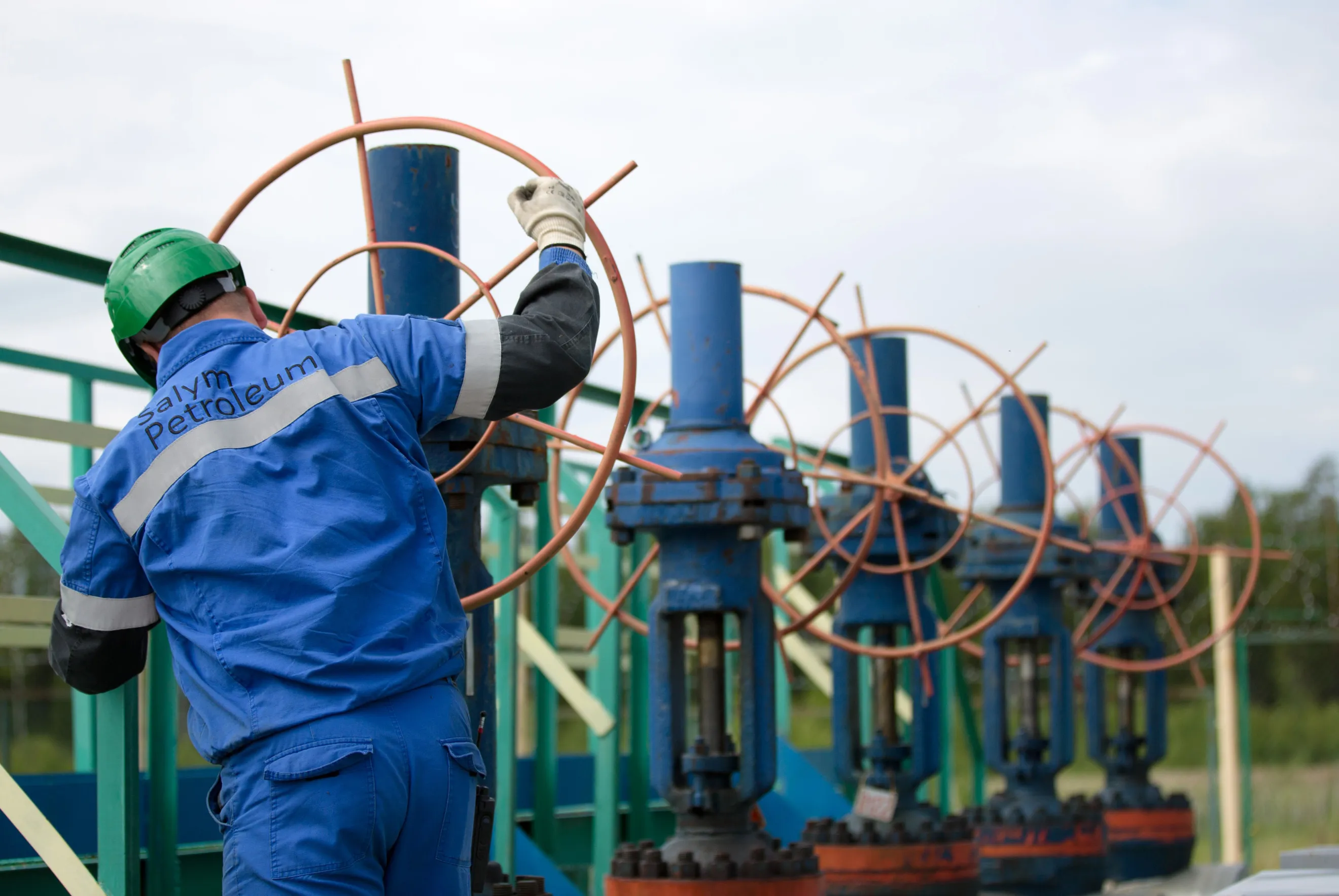 A worker adjusts a valve wheel on pipework at an oil plant in Salym, Russia.
