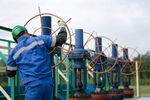 A worker adjusts a valve wheel on pipework at an oil plant in Salym, Russia.