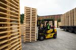 An employee uses a forklift truck to move a stack of heat treated wooden pallets in Huddersfield.
