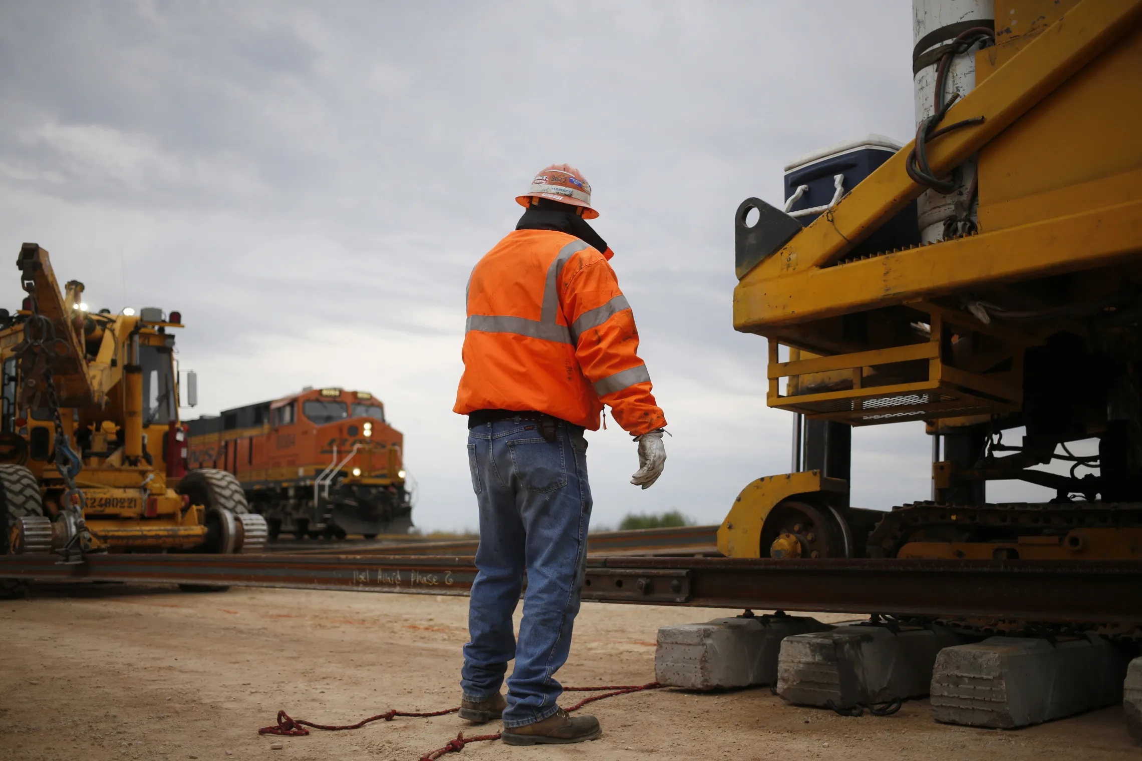 A rail worker watches as a freight train passes on the Burlington Northern Santa Fe (BNSF) Southern Transcontinental line in Alva, Oklahoma.