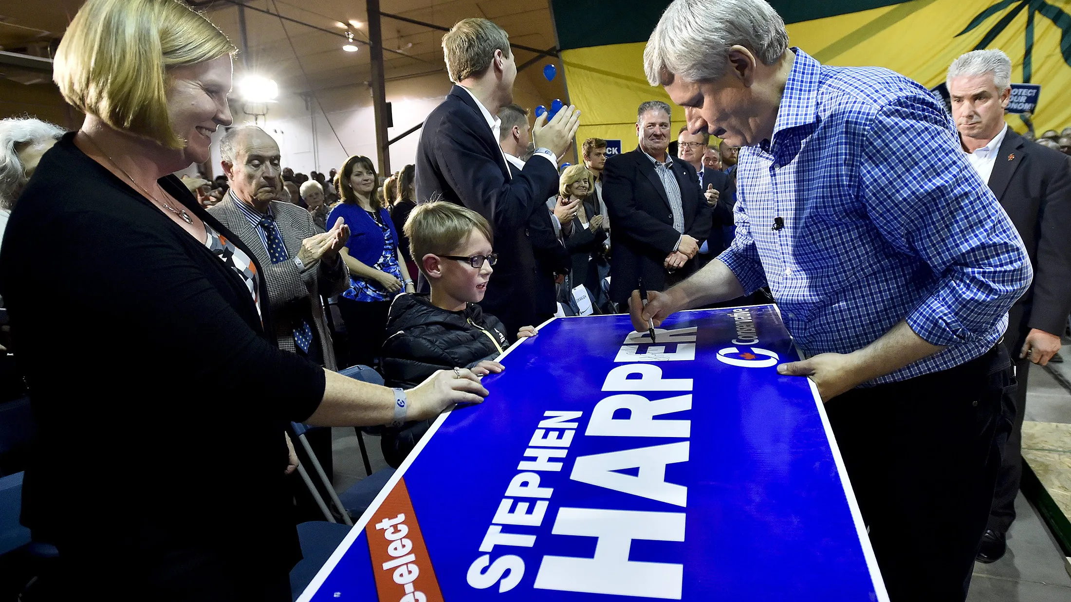 Stephen Harper, right, signs a campaign sign after speaking in Saskatoon, on Oct. 6.
