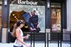 A pedestrian walks past a shop with a broken window due to protests in the SoHo neighborhood of New York.