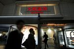 Pedestrians walk past illuminated signage for Daiwa Securities Co. displayed outside one of the company's branches at night in Tokyo, Japan.
