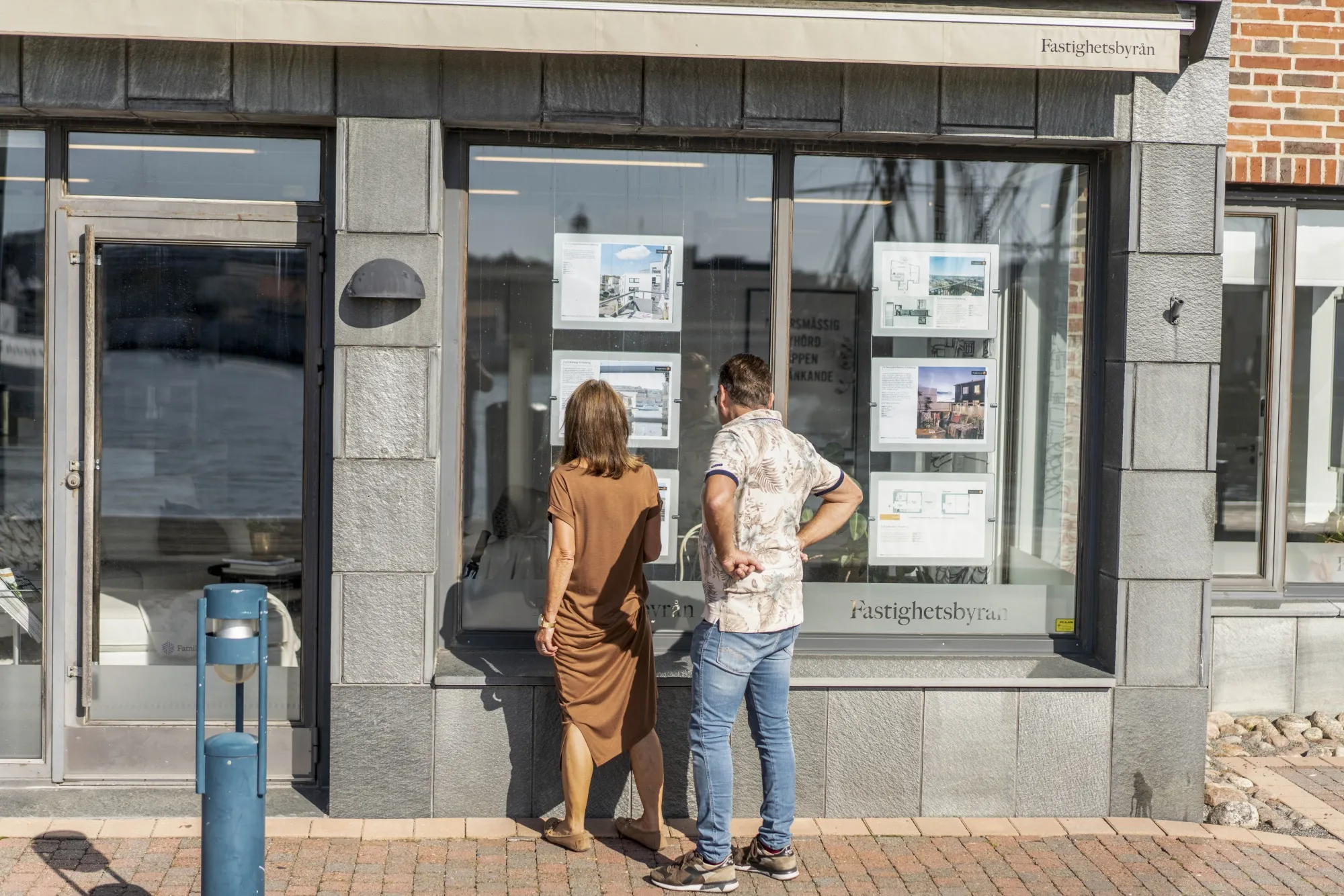 Pedestrians look at property listed in a real estate agent's window in the Eriksberg district of Gothenburg.