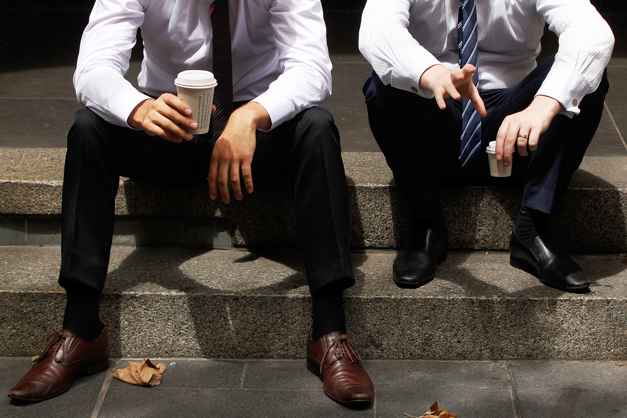 Office workers sit with cups of coffee n the central business district of Sydney, Australia.
