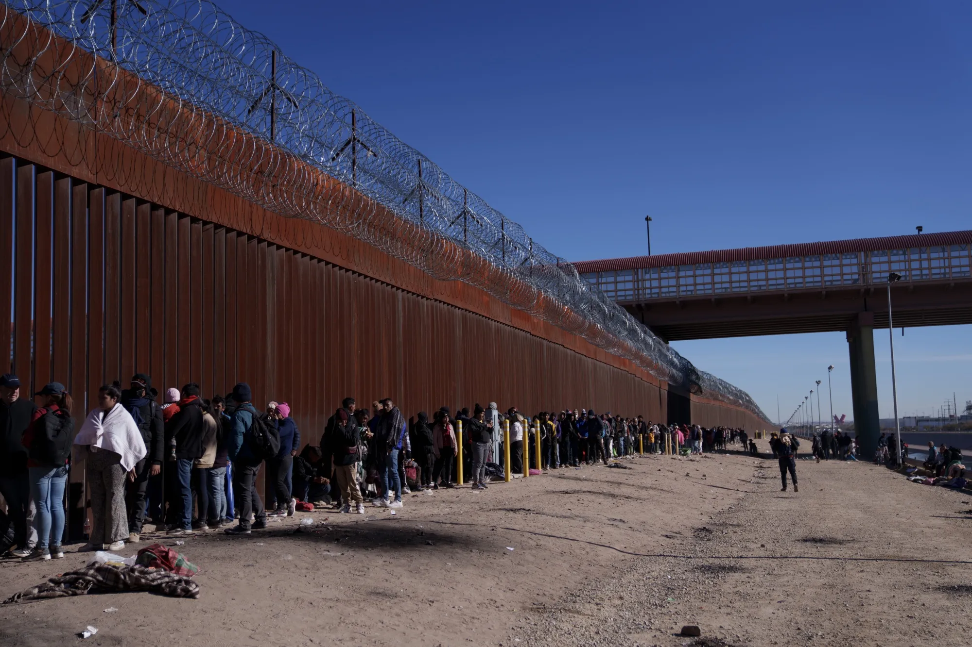 Migrants wait at the US and Mexico border wall in El Paso, Texas.