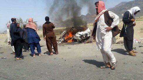 This photograph taken on May 21, 2016 shows Pakistani local residents gathering around a destroyed vehicle hit by a drone strike in which Afghan Taliban Chief Mullah Akhtar Mansour was believed to be travelling in.