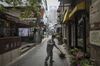 A man wearing a protective mask sweeps a lane in front of stores in the Tianzifang retail precinct in Shanghai, China, on Monday, April 20, 2020. Chinese banks lowered borrowing costs and the government promised to sell another 1 trillion yuan ($141.3 billion) in bonds to pay for stimulus spending after the economy had its first contraction in decades due to the coronavirus outbreak.