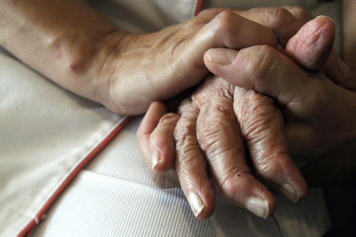 A nurse holds the hands of a person suff