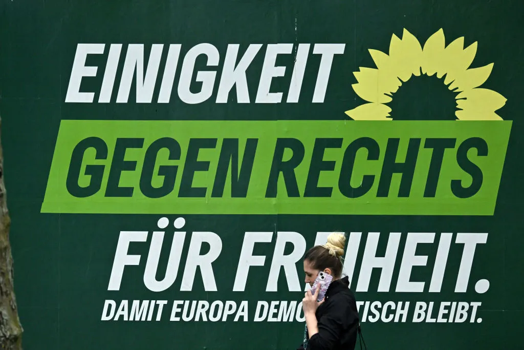 A woman walks past an election poster of the Greens party in Frankfurt.