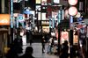 Pedestrians walk past restaurants at night in the Shinjuku district of Tokyo, Japan, on Thursday, Nov. 19, 2020. Tokyo raised its Covid-19 alert to the highest of four levels, as daily infections in the Japanese capital increased by more than 500 for the first time amid a resurgence of the pathogen across the country.
