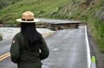 A Yellowstone National Park ranger is seen standing near a road wiped out by flooding along the Gardner River the week before, near Gardiner, Mont., June 19, 2022. Park officials said they hope to open most of the park within two weeks after it was shuttered in the wake of the floods. (AP Photo/Matthew Brown)