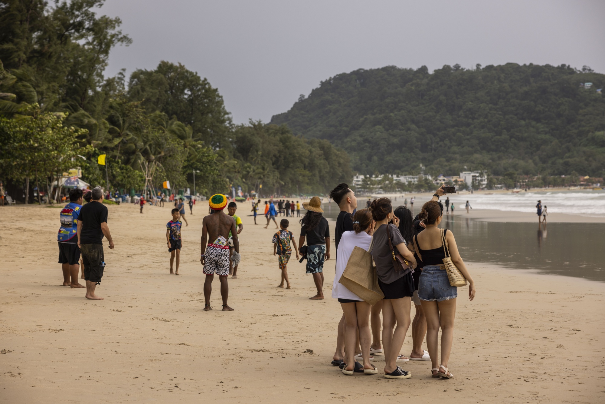 Tourists take a selfie photograph on Patong Beach in Phuket, Thailand.