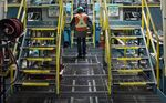 A worker walks past a machine that sorts lumber into grades and sizes at a mill in Thunder Bay, Canada, Ontario.
