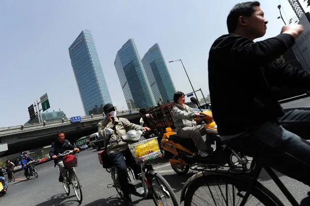 Bicycle commuters ride past high-rises in Beijing in 2011