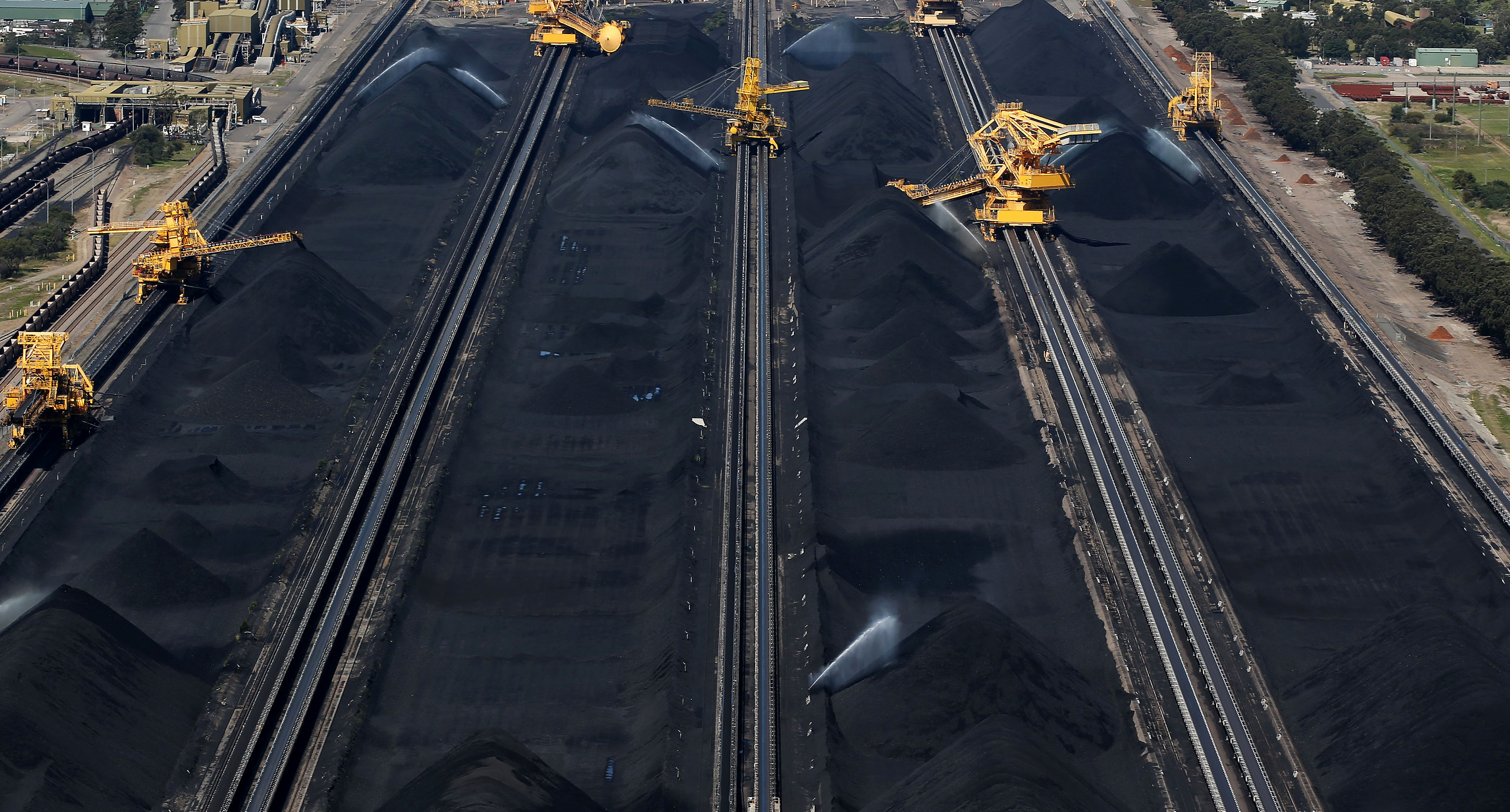 Stacker-reclaimers operate next to stockpiles of coal in Newcastle, Australia.