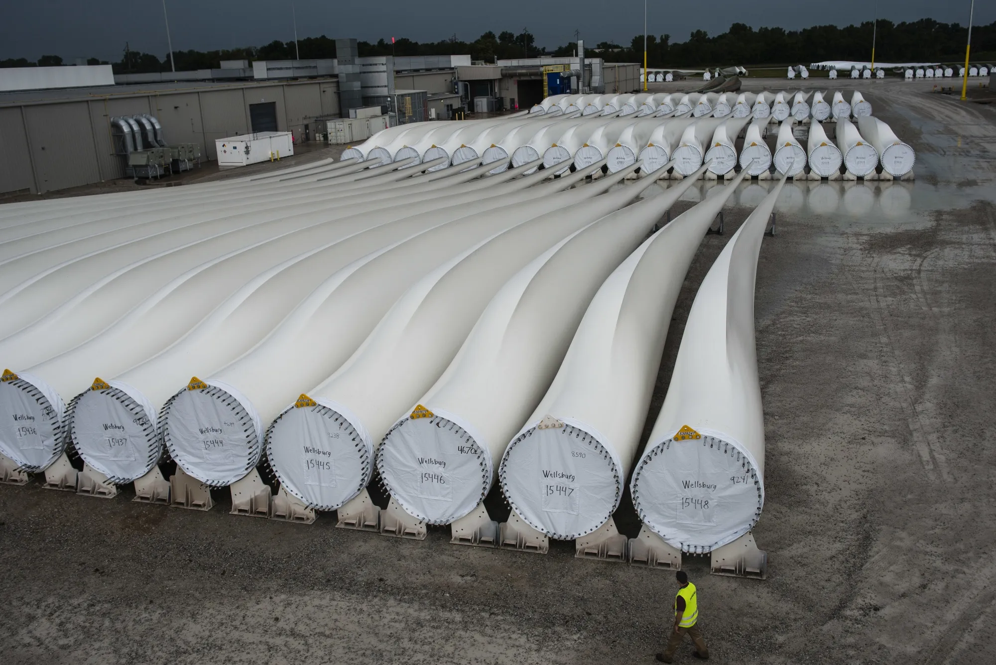 A worker walks past wind turbine blades awaiting transport in Fort Madison, Iowa.