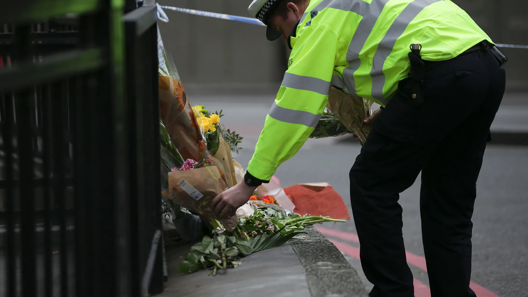 A police officer lays flowers at a police cordon at the north end of London Bridge in London on June 4, 2017, to add to tributes piled their to the victims of the June 3 deadly terror attack. Seven people were killed in a terror attack on Saturday by three assailants on London Bridge and in the bustling Borough Market nightlife district, the chief of London's police force said on Sunday. / AFP PHOTO / Daniel LEAL-OLIVAS (Photo credit should read DANIEL LEAL-OLIVAS/AFP/Getty Images)
