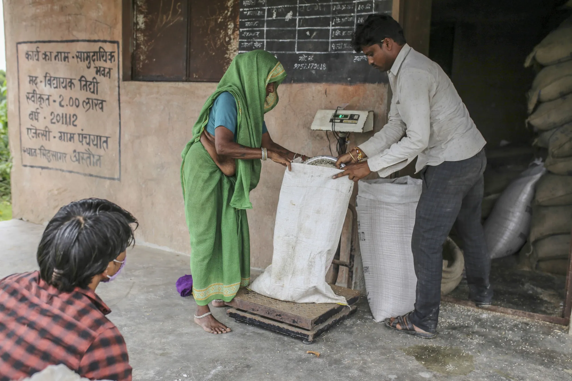 A woman collects grain from a state-run distribution store in a village in Tikamgarh district, Madhya Pradesh, India.
