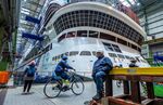 A shipbuilder in front of the stern of the "Global Dream" cruise ship under construction, in Wismar.