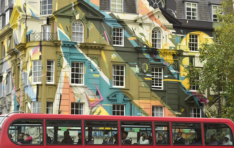 Passengers ride in a London bus past a brightly painted building in the Kings Cross area of central London October 22, 2014.