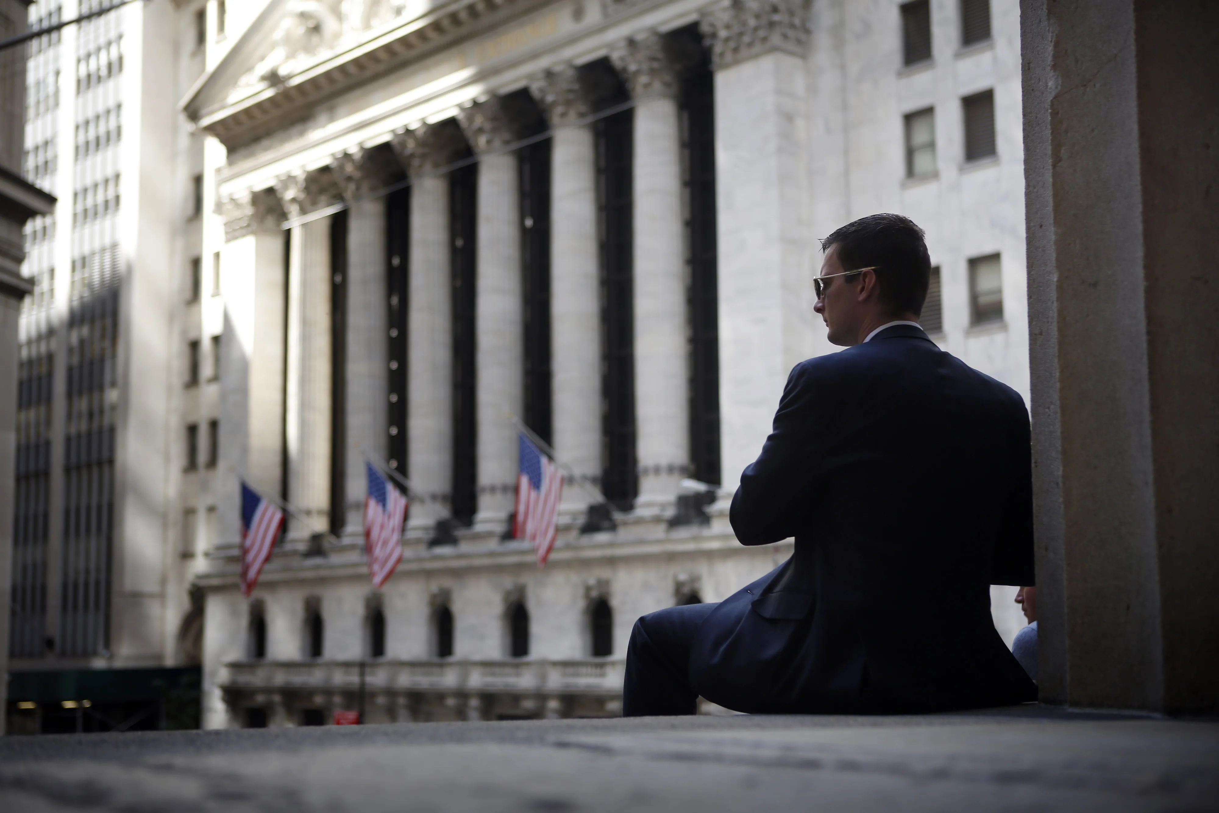 A man sits on the steps of Federal Hall across from the New York Stock Exchange (NYSE) in New York, U.S., on Friday, Sept. 26, 2014. The S&amp;P 500 finished the quarter below its average price for the past 50 days after dropping under that level for the first time since August on Sept. 25.
