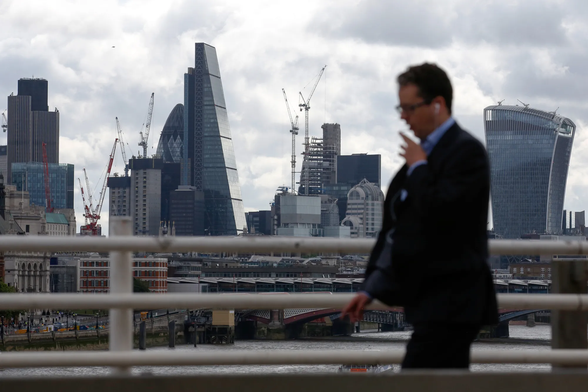 A commuter crosses Waterloo Bridge, in view of City of London skyscrapers, following Saturday night's terror attack, in London, U.K., on Monday, June 5, 2017. Police are stepping up drills and security on the streets as the challenge facing them continues to shift.