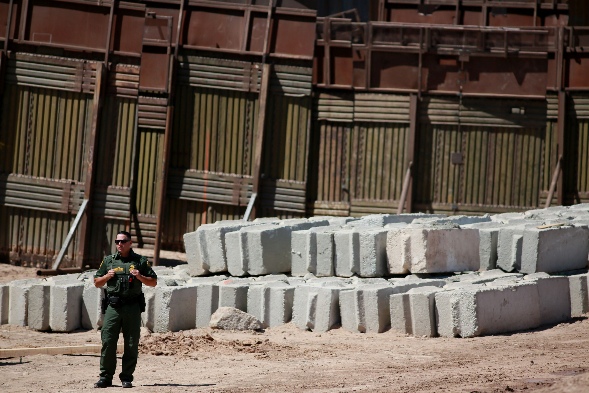 A U.S. Border Patrol agent stands guard in front of border wall construction in Calexico, California, on Wednesday, April 18, 2018.&nbsp;
