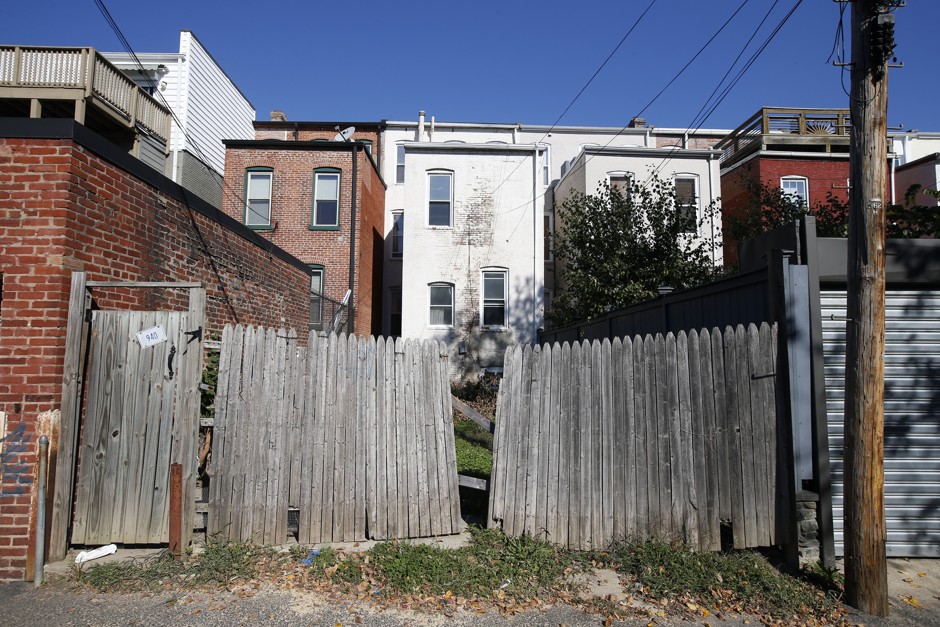 A run-down fence opens onto the backs of several row houses. 