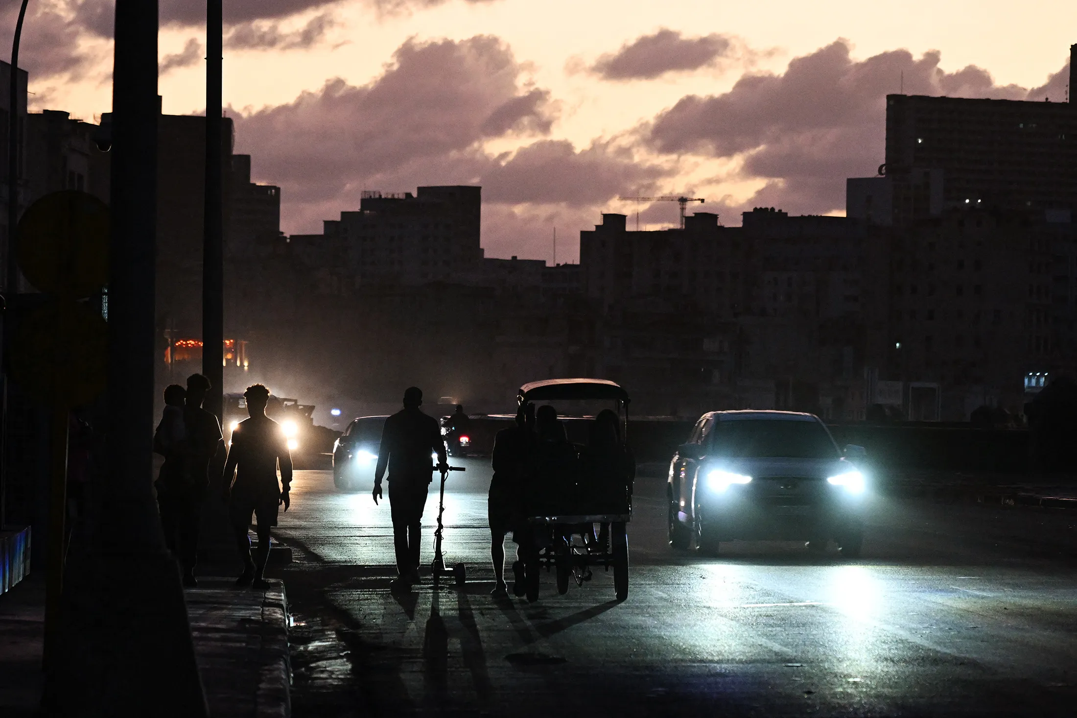 Pedestrians walk beside traffic during a nationwide blackout in Havana on March 21.
