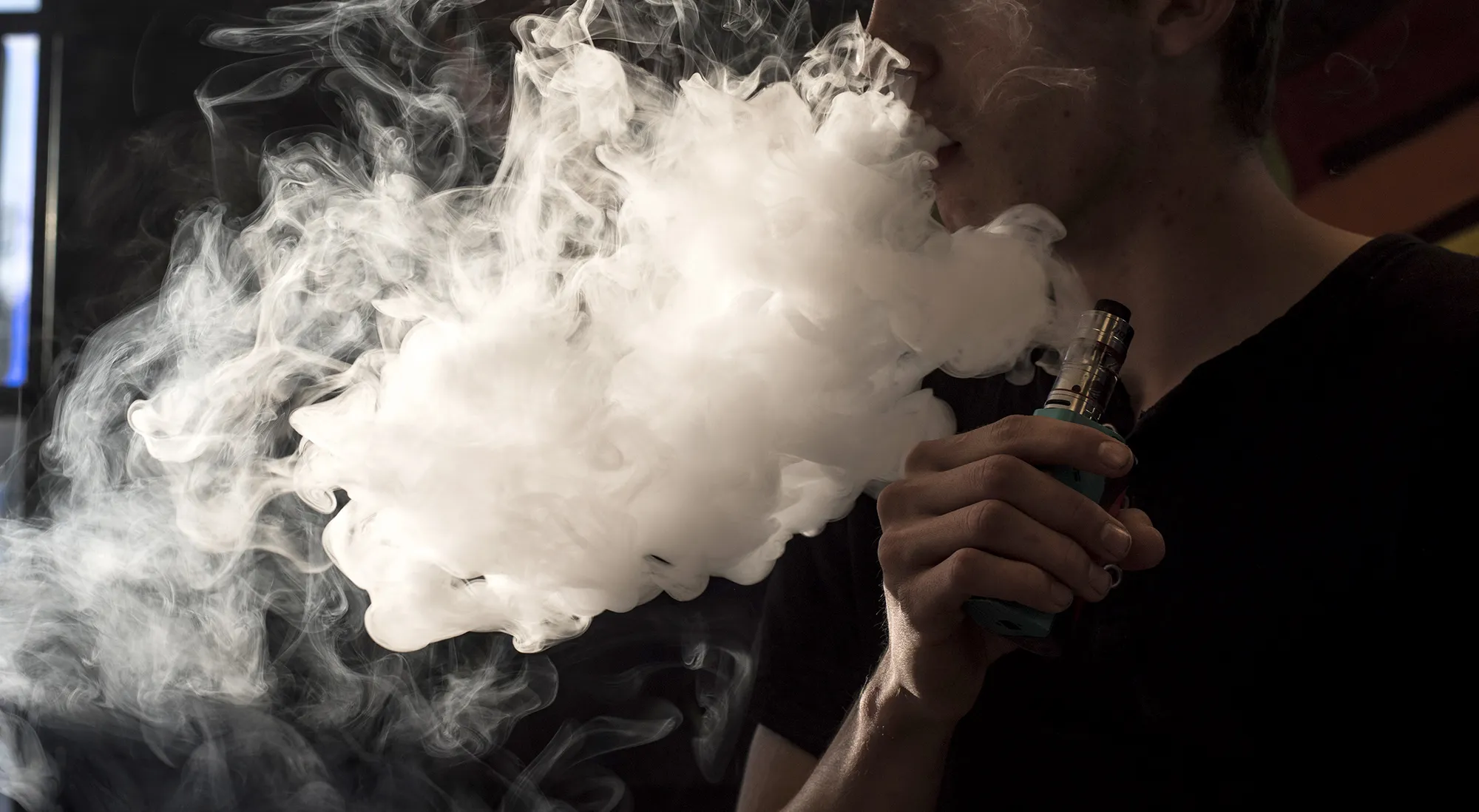 An&nbsp;employee exhales vapor while smoking an electric cigarette.