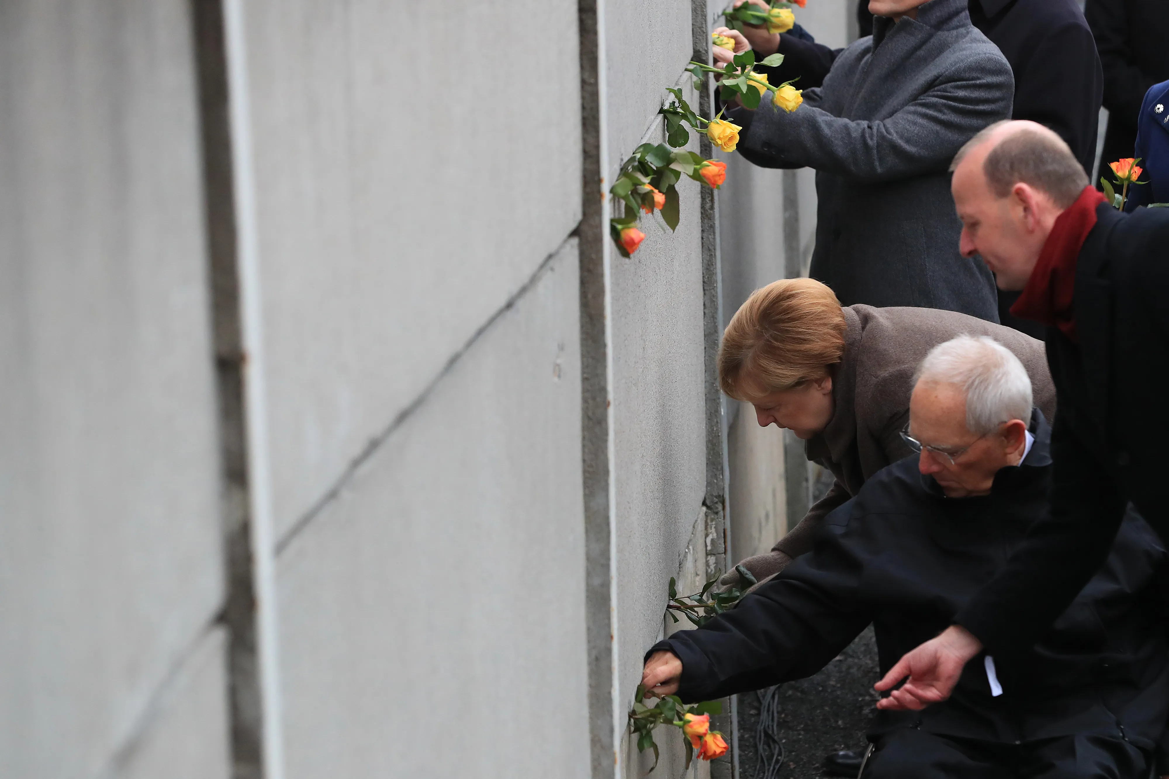 Angela Merkel and Wolfgang Schaeuble place roses into a portion of the wall at Bernauer Strasse on Nov. 9.&nbsp;