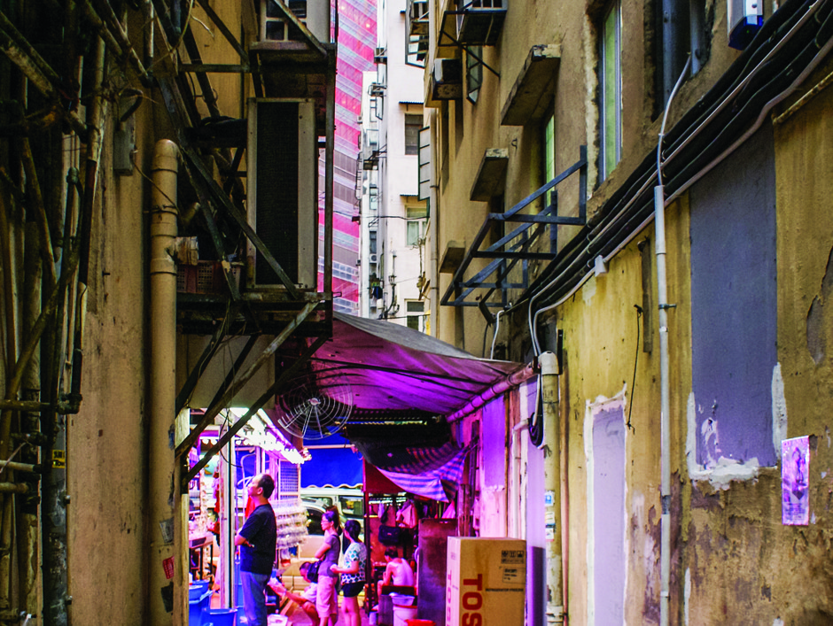 An alleyway in Tsim Sha Tsui is illuminated by the pink glow of a small fish store.