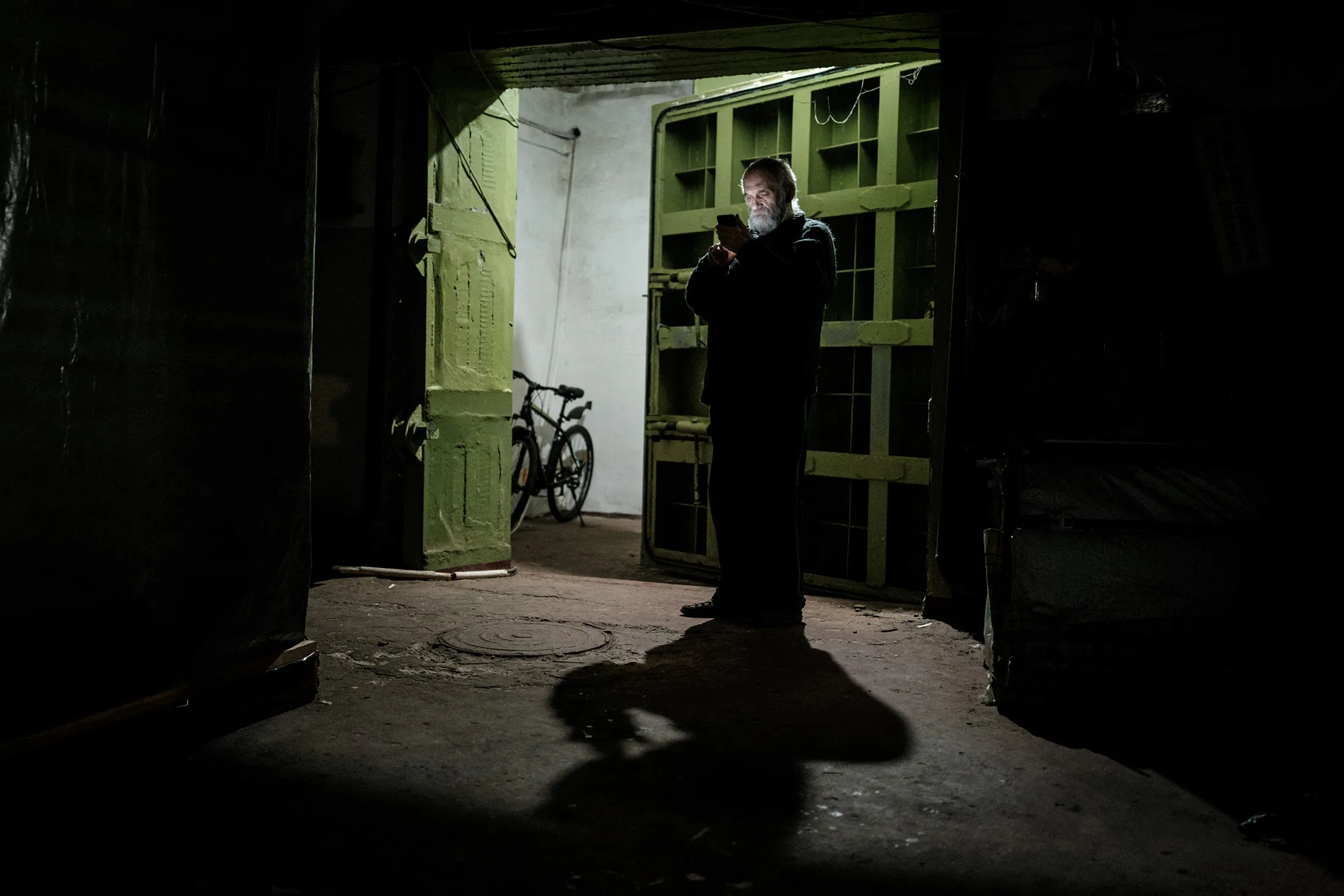 An elderly man uses his smartphone at the entrance of the bunker of Ostchem factory in Severodonetsk, eastern Ukraine.