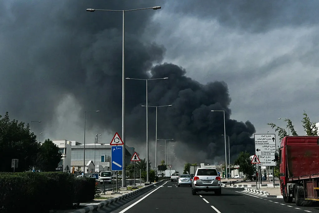 TOPSHOT - Motorists drive past a plume of smoke rising from a reported Iranian strike, in Doha on March 1.