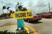 Felipe Castro holds a sign advertising a tax preparation office on April 14, 2010, in Miami.