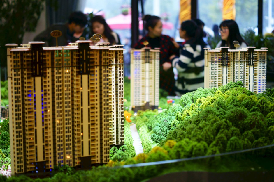 People look at miniature models of new apartments at a property sale center in China's Hubei province.