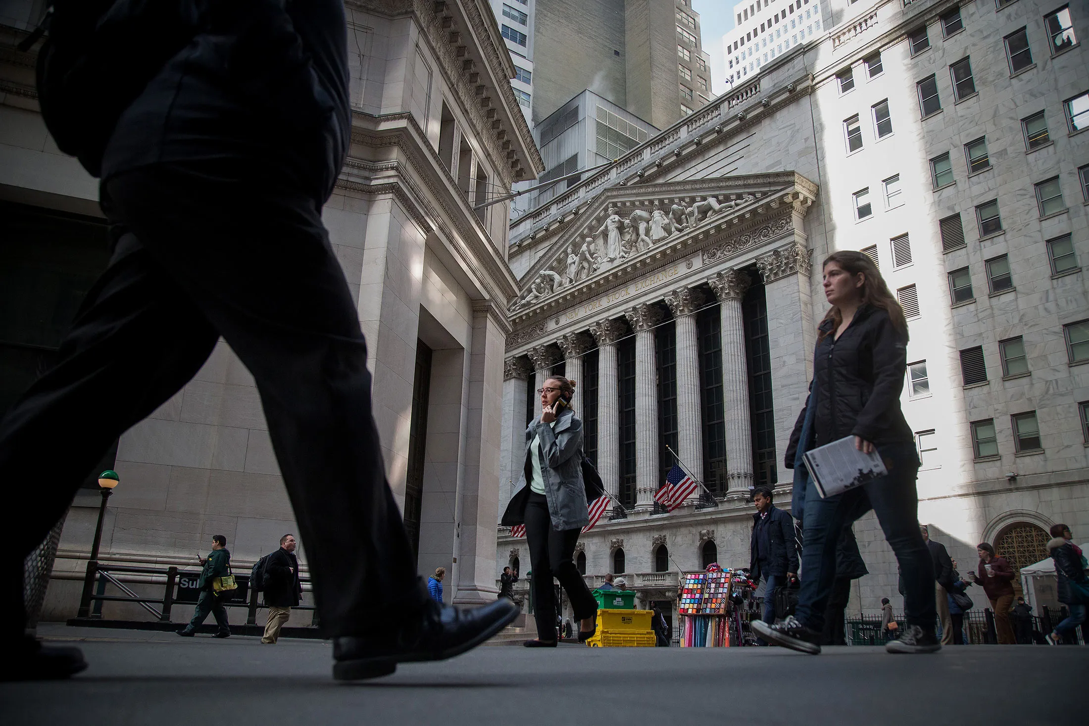 Pedestrians walk past the New York Stock Exchange (NYSE) in New York, U.S., on Thursday, March 24, 2016. Stocks dropped around the world as the dollar extended gains into a fifth day, with the potential for higher U.S. interest rates again roiling financial markets as the Easter vacation looms.
