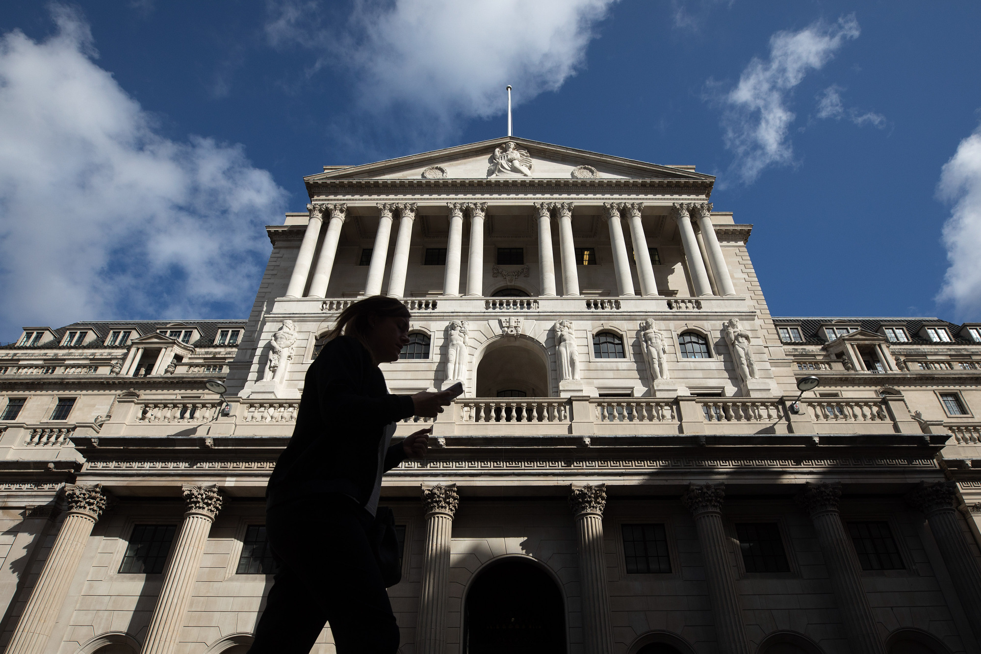 A pedestrian walks past the Bank of England in the City of London, U.K., on Monday July 31, 2017. Consumer credit growth slowed in June after the Bank of England officials took action to limit some areas of risk of borrowing.