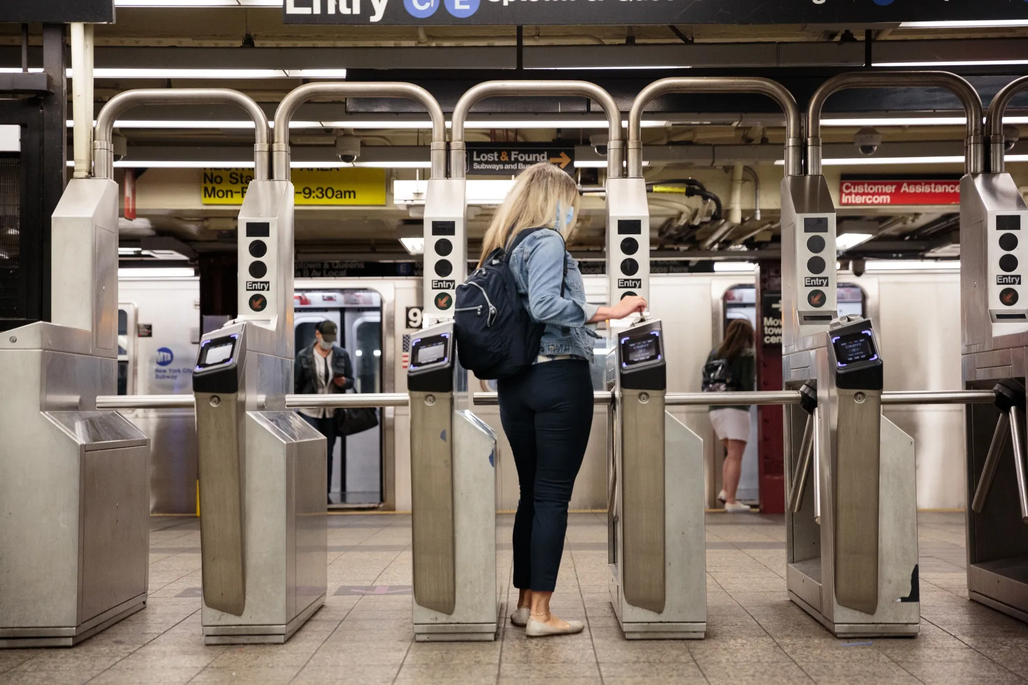A commuter swipes a metro card through a turnstile slot at a subway station in New York.