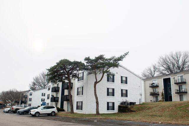 Picture of the Oak Park Apartment complex. Each unit has a small balcony, the buildings are 3-story high. There are cars parked, but nobody is outside.